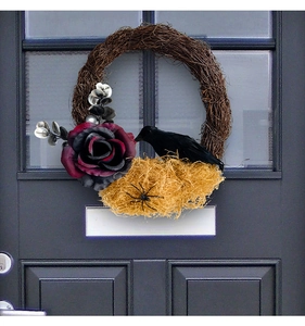 Primer plano de corona de Halloween con cuervo negro, rosa oscura y araña en la puerta