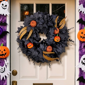 Halloween wreath with black maple leaves and glitter pumpkins hanging on a white front door