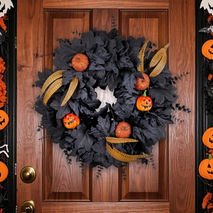 Halloween wreath with black maple leaves and orange pumpkins on dark wooden door