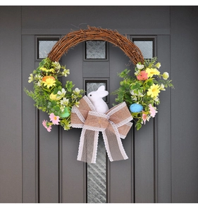 Close-up of Easter wreath with burlap bow and rabbit model on a dark front door