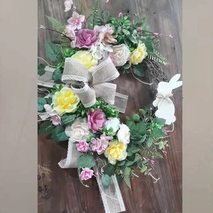 Detail of Easter wreath with floral silk roses, burlap bow, and white rabbit silhouette