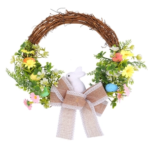 Easter wreath with natural vine, foam bunny, colorful eggs and green leaves on white background