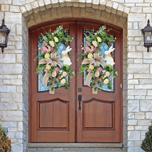 Close-up of Easter wreath with faux roses, burlap bow and rabbit on wooden door