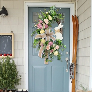 Easter wreath with pastel roses and burlap bunny bow hanging on a blue front door