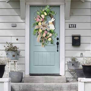 Detail of Easter wreath with pink roses, white bunny silhouette, and burlap bow on blue door