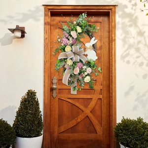 Close-up of Easter wreath with colorful roses and rabbit decor on a rustic wooden door