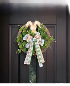Close-up of Easter wreath with rabbit ears and green leaves on dark wooden door
