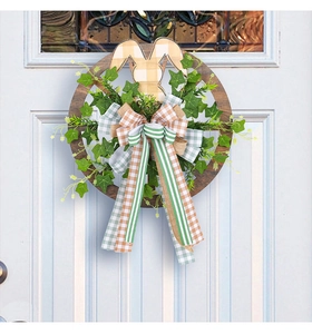Easter wreath with bunny ears, greenery and Happy Easter sign on a white door