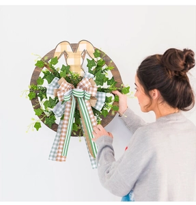 Detail of Happy Easter wooden wreath with bunny ears, green ivy leaves and festive bow