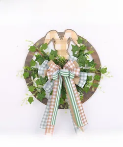 Close-up of Easter wreath with wooden bunny, green leaves, and checkered ribbon bow