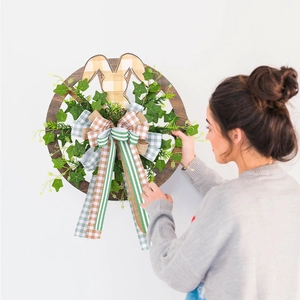 Easter wreath with green leaves, wooden bunny silhouette and plaid bow wall decoration