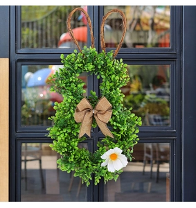 Detail of bunny-shaped Easter wreath with artificial greenery and a burlap bow on a window