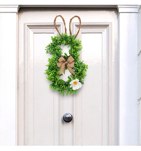 Detailed close-up of Easter rabbit wreath with green leaves and burlap bow on white door