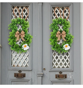 Detail of bunny-shaped Easter wreath with artificial greenery and burlap bow on gray door