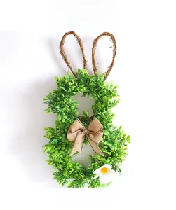 Detail of Easter bunny wreath with green leaves, rattan ears, and a jute bow decoration