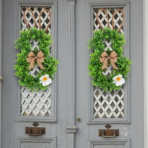 Symmetric Easter bunny wreath with artificial greenery and rustic burlap bow on grey door