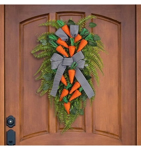 Detail of Easter door wreath with hanging orange carrots, green ferns and striped bow