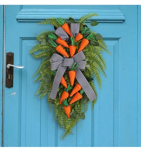 Close-up of Easter carrot wreath with fern leaves and striped bow on a blue door