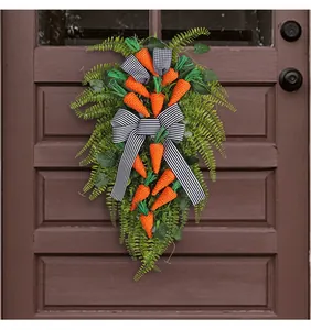 Detail of Easter carrot door hanging with orange twine and faux greenery on dark wood