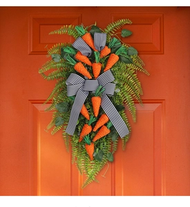 Close-up of Easter carrot door swag with artificial greenery and striped bow decoration