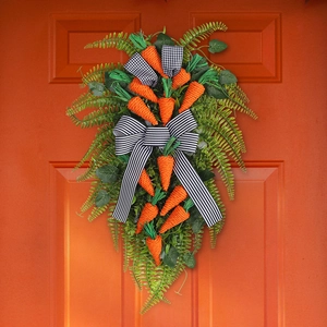 Easter carrot wreath with green leaves and black-white striped bow on orange door
