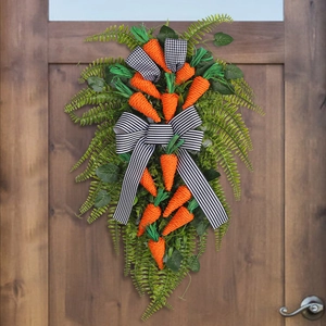 Easter carrot wreath swag with green ferns and black white striped bow on wooden door