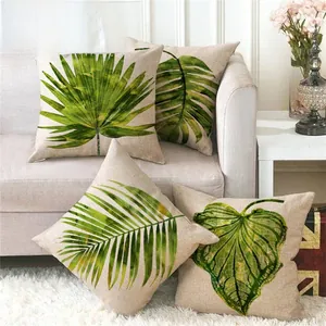 Set of four linen cushion covers with green tropical leaf patterns on a grey sofa