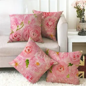 Detail of four linen pillow covers with pink rose floral patterns on a sofa