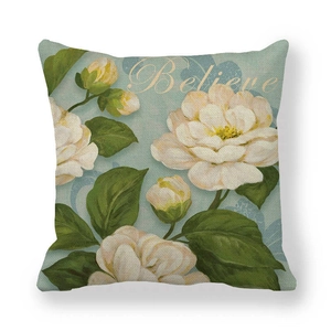 Close-up of linen cushion cover with oil painting camellia pattern and 'Believe' text