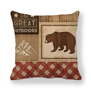 Dettaglio del copricuscino in lino con silhouette di orso e motivi grafici outdoor