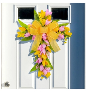 Dettaglio ghirlanda pasquale a croce con tulipani e fiocco su porta in legno bianca