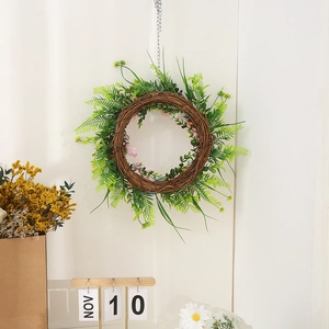 Paaskrans met groene varens en roze knoppen op een witte achtergrond van de muur