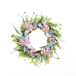 Paaskrans met gekleurde eieren, roze bloemen en witte konijntjes op groene bladeren