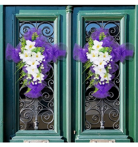 Dettaglio ghirlanda pasquale a croce in rete viola con gigli su porta verde