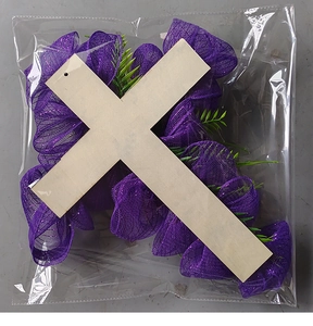 Dettaglio della croce pasquale in legno con tessuto a rete viola e foglie artificiali