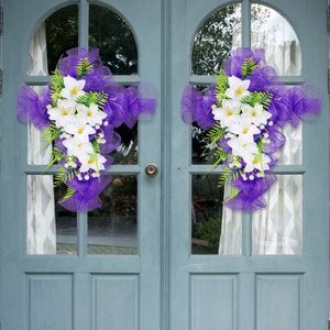 Ghirlanda pasquale a croce in rete viola con fiori artificiali su porta blu