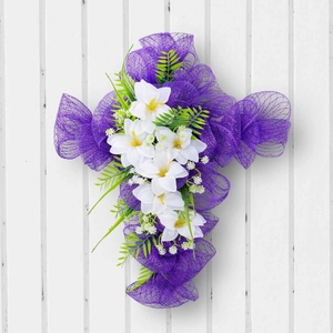 Ghirlanda pasquale a croce in rete viola con gigli bianchi su fondo in legno bianco