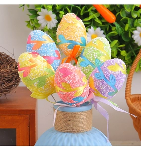 Close-up of colorful Easter egg picks with ribbons and leaves in a blue ceramic vase