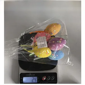 Colorful Easter foam eggs with glitter and hanging ribbons shown on a digital scale