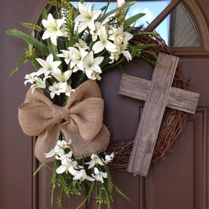 Easter wreath with cross and white lilies on rustic wooden door decoration