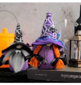 Close-up of Halloween gnome plush with spider patterns and orange braids on book props