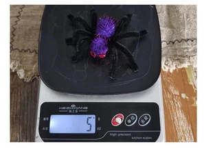 Vue macro d'une pince à cheveux araignée en peluche violette de 5g sur une balance