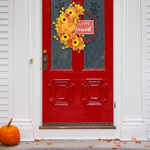 Dettaglio ghirlanda autunnale con girasoli e targa Happy Harvest su porta rossa