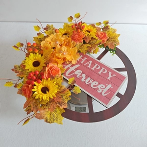 Dettaglio ghirlanda autunnale con girasoli e targa Happy Harvest su ruota di legno
