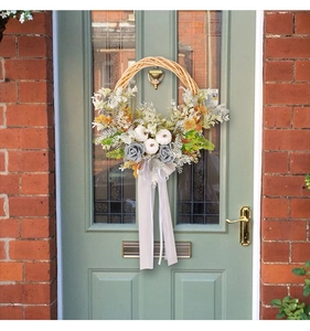 Détail de couronne d'automne avec mini citrouilles, fleurs et rubans sur porte en bois
