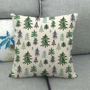 Close-up of linen pillowcase with green Christmas tree patterns on a grey sofa