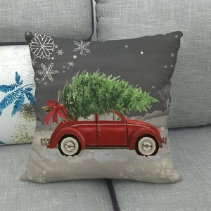 Christmas car linen throw pillow cover with red auto and green tree on a gray sofa