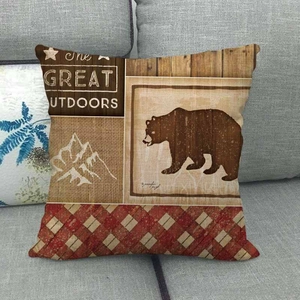Linen Christmas pillow cover with Great Outdoors bear print on a gray sofa