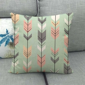 Detailed view of linen cushion cover with arrow pattern on a grey fabric sofa