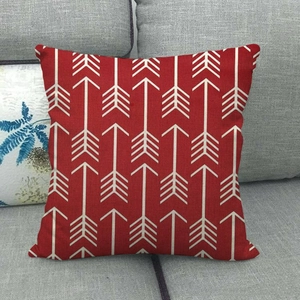 Detail of red linen pillowcase featuring white arrow patterns on a grey fabric sofa